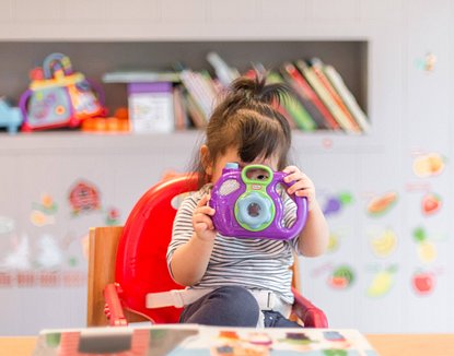 Image of toddler using toy camera
